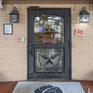 A building entrance featuring a decorative door with a star design, flanked by exterior lanterns and set against a brick wall.