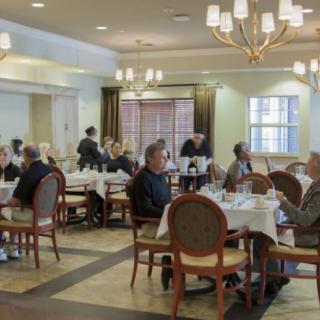 A dining room with patrons seated at tables, enjoying their meals in a warmly lit restaurant setting.