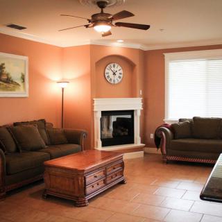 A cozy living room with comfortable sofas, a wooden coffee table, and a fireplace under a clock.