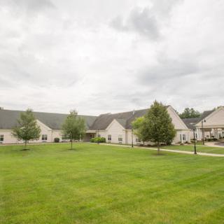 A view of a suburban residential area featuring well-maintained buildings and lush green lawns under a cloudy sky.