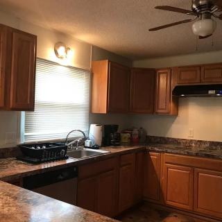 A clean kitchen with wooden cabinets and a ceiling fan.