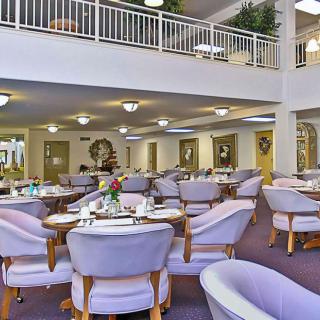 A spacious and elegantly designed dining area with multiple tables and chairs, featuring soft lighting and tasteful decor.