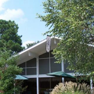 A modern building surrounded by lush greenery and trees under a clear blue sky.