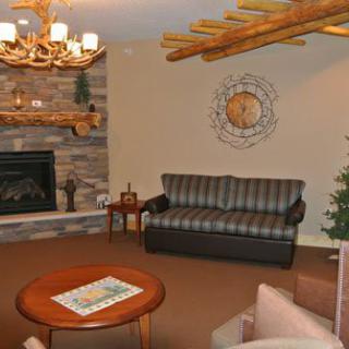 A cozy living room with a stone fireplace, comfortable couch, and rustic wooden beams.