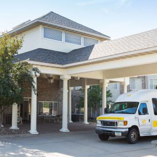 A building entrance with a van parked nearby.
