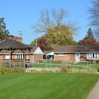 A peaceful residential area featuring a gazebo, well-maintained grass, and colorful autumn trees.