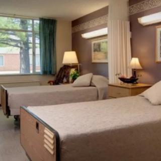 A hospital room with two beds and a window view.