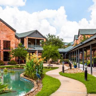 Beautiful outdoor scene with modern buildings, a scenic pond, and lush greenery.