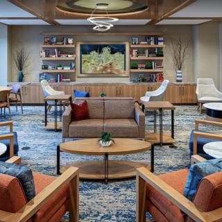 A modern lounge area featuring a seating arrangement with chairs and couches, decorated with artwork and bookshelves.