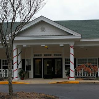 A welcoming entrance to a residential building with decorative columns and trees nearby.