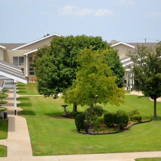 A view of a landscaped courtyard with buildings, trees, and well-maintained lawns.