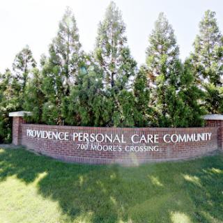 Welcome sign for the Providence Personal Care Community, surrounded by trees.