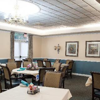 A cozy dining area with neatly arranged tables and comfortable chairs, featuring soft lighting and tasteful decor.