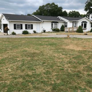 A suburban house with a large front lawn under cloudy skies.