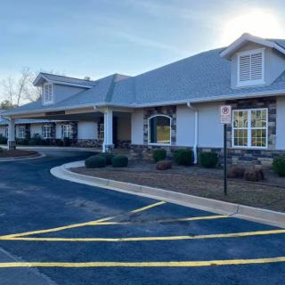 A view of a modern building with a driveway and parking lot on a sunny day.
