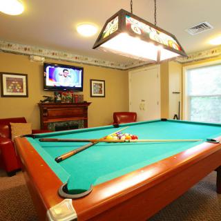A cozy game room featuring a pool table, wall-mounted TV, and comfortable seating.
