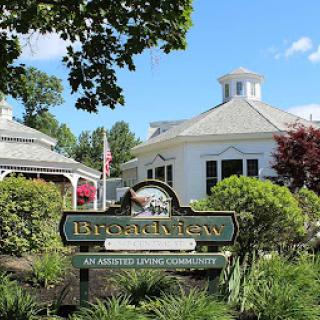 A welcoming entrance sign to the Brookhaven community, surrounded by lush greenery and a beautiful building in the background.