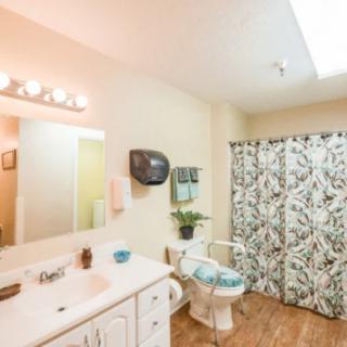 A well-lit bathroom featuring a sink, mirror, and patterned shower curtain.