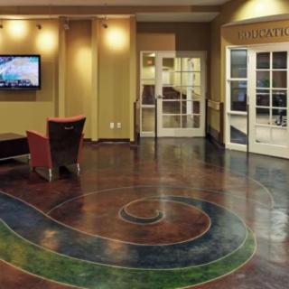 A modern lobby featuring a unique floor design and a seating area with a television.