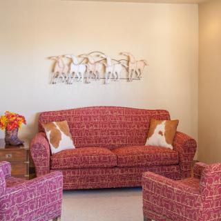A cozy living room with red patterned furniture and decorative wall art.