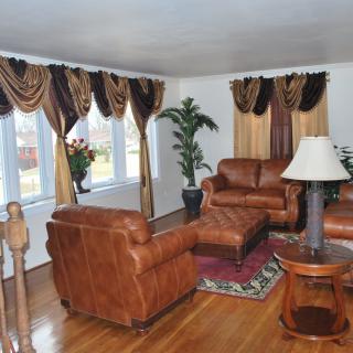 A cozy living room with leather furniture and elegant drapes.
