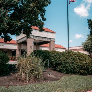 The entrance of a library surrounded by well-maintained landscaping and a flagpole.