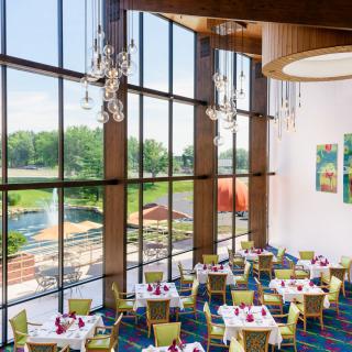 A modern restaurant interior with large windows and elegantly set tables.