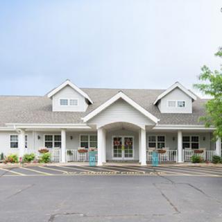 A large, white residential building with a symmetrical design and a welcoming front porch.