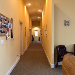 A well-lit hallway with yellow walls and carpet, featuring decorative frames on the sides.