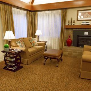 A cozy living room with warm lighting, featuring a sofa, coffee table, lamps, and a fireplace.