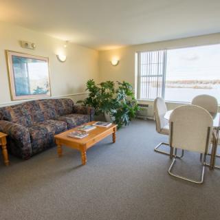 A cozy living room with a comfortable sofa and a dining area, decorated with indoor plants and modern furnishings.