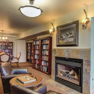 Cozy library room with bookshelves, a fireplace, and comfortable seating.