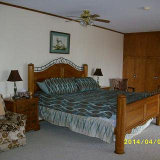 A cozy bedroom with a wooden bed frame and striped bedding, accompanied by nightstands and lamps.