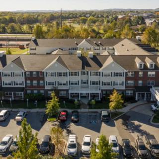 Aerial view of a suburban residential building with a parking lot surrounded by trees.