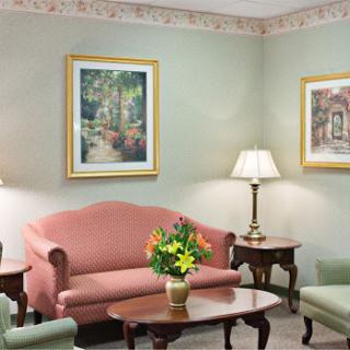 A cozy living room setup featuring a pink sofa, green chairs, and decorative art on the walls.
