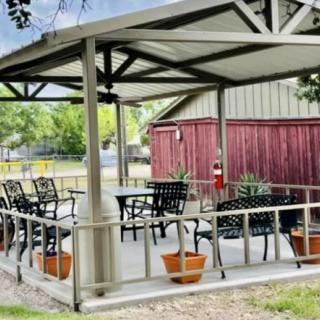 An inviting outdoor patio with a shaded seating area, complete with chairs, tables, and potted plants.