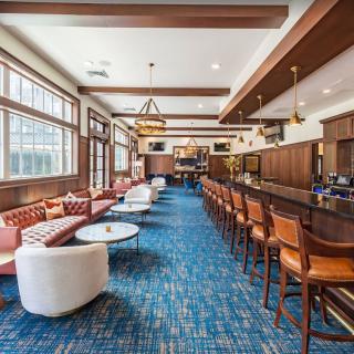 A modern lounge and bar area with comfortable seating, wooden accents, and large windows.