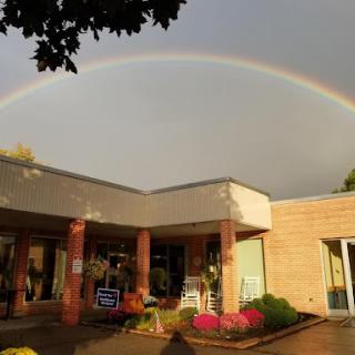 A beautiful rainbow arcs over a charming building, creating a vibrant scene.