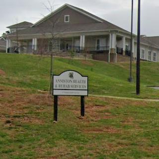 A view of a residential building with a sign in front, surrounded by grassy land.