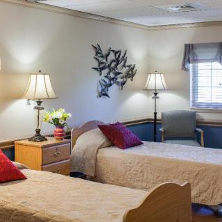 A cozy bedroom with two single beds, decorated with lamps and wall art.