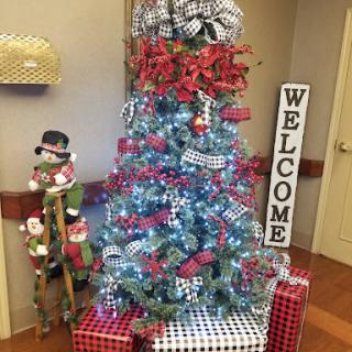 A beautifully decorated Christmas tree with presents and a cheerful welcome sign.