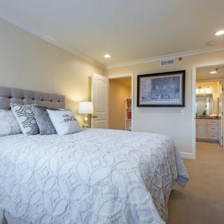 A modern bedroom with a neatly made bed, decorative pillows, and warm lighting.
