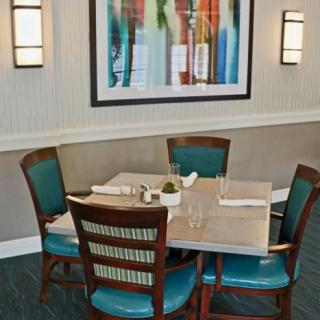 A restaurant dining area with a set table and colorful artwork on the wall.