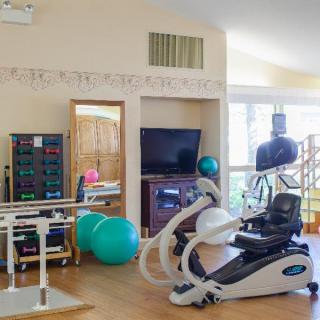 A home gym featuring various exercise equipment including an exercise bike, dumbbells, and medicine balls.