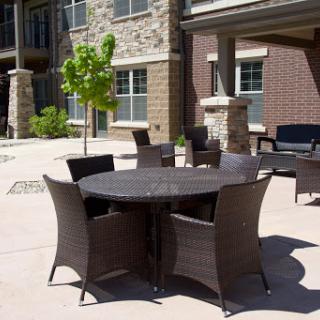 A modern outdoor furniture set featuring a round table surrounded by stylish chairs, set against a backdrop of stone buildings.