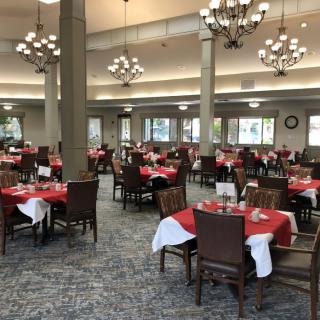 An elegant dining hall with tables set with red tablecloths and chandeliers hanging from the ceiling.