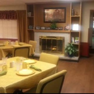A cozy dining room with multiple tables set for a meal, featuring a fireplace and decorative elements.