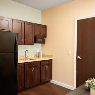 A modern kitchen with dark wooden cabinets, a black fridge, and a small countertop area.