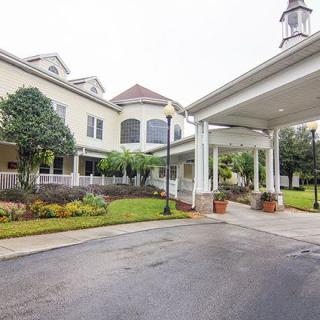 A beautifully landscaped entrance to a large building with a covered driveway.