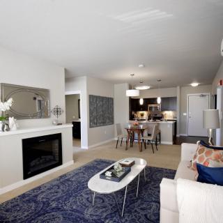 A modern living room with a dining area, featuring a fireplace and elegant furnishings.